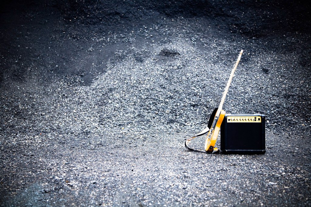 An electric guitar leaning against a guitar amplifier, set against a textured dark background.